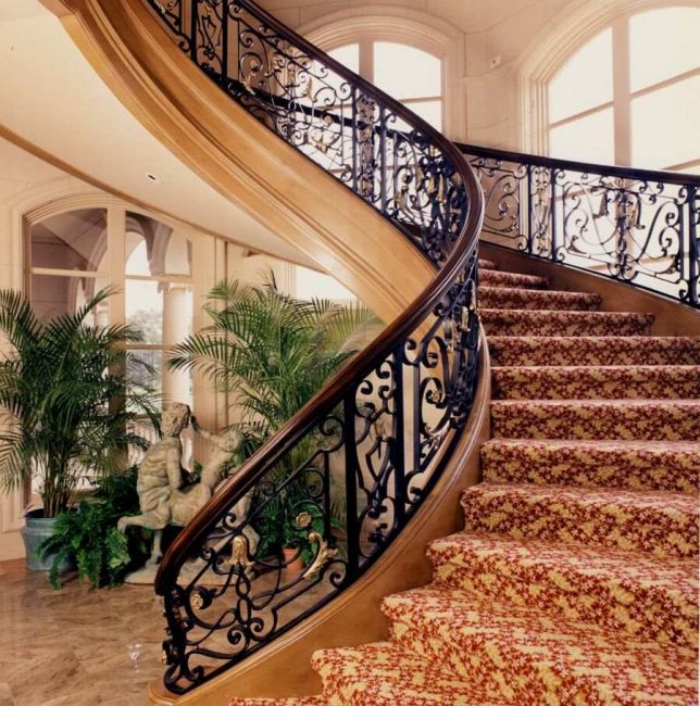 De combinatie van smeden, hout en tapijt in het ontwerp van de trap